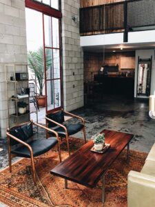 salon de type industriel avec sol en béton ciré et mur bruts, très haut de plafond