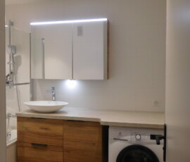 APRÈS TRAVAUX Salle de bain rénovée avec baignoire, lave-linge intégré et ambiance chaleureuse